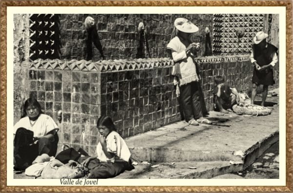 Indigenas parados frente a la fuente de azulejos con caras en Valle de Jovel.